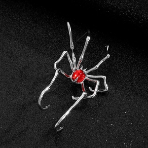 Gothic silver spider ear cuff with a vibrant red gemstone on a dark textured background