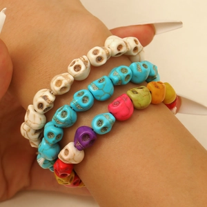 Gros plan sur un ensemble de trois bracelets à perles de crâne en blanc, bleu et multicolore