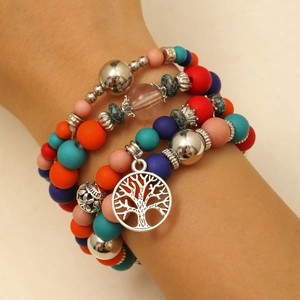 Detail van gelaagde bohemian kralenarmbanden met kleurrijke kralen en levensboom hanger
