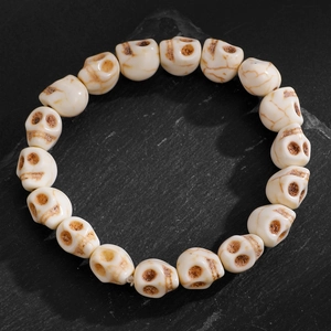 Bracelet gothique avec perles de crâne en résine turquoise blanche sur fond en ardoise noire