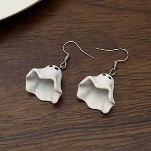 Gros plan de boucles d'oreilles fantômes blanches sur fond en bois pour Halloween