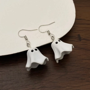 Vue détaillée des boucles d'oreilles fantômes d'Halloween au fini mat sur bois rustique