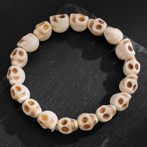 Gros plan d'un bracelet de perles tête de mort avec gravures sur pierre sombre