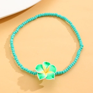 Detalle de la tobillera de cuentas verde azulado con colgante de flor de frangipani