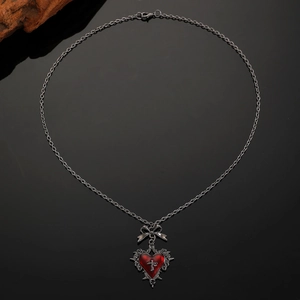 Macro detail of gothic heart pendant with cross and bow on dark metallic chain