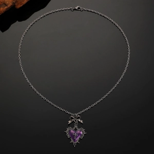 Macro detail of Gothic bow connector and purple heart cross pendant on vintage chain