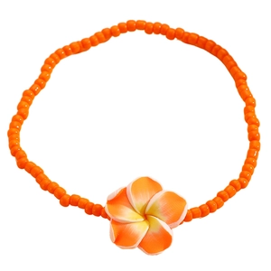 Detalle de tobillera con cuentas naranjas y colgante de flor de frangipani para playa