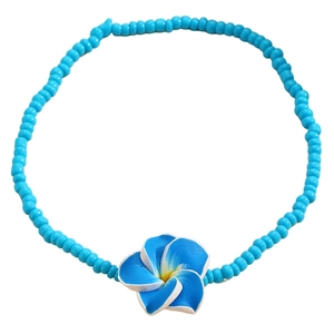 Detalle de tobillera de cuentas azules con colgante de flor de plumeria para la playa