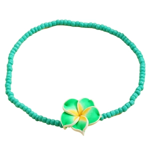 Detalle de una tobillera bohemia de cuentas turquesas con una flor de plumeria de resina