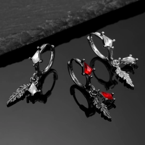 Macro shot of vintage dark metal feather earrings with geometric zircon star stones