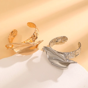 Dettaglio di bracciali martellati oro e argento con design floreali in metallo astratto