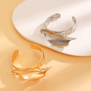 Dettaglio di bracciali oro e argento con metallo plissettato organico e trama martellata