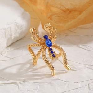 Détails d'une bague araignée dorée sertie de gemmes bleu foncé et reliefs de perles fines