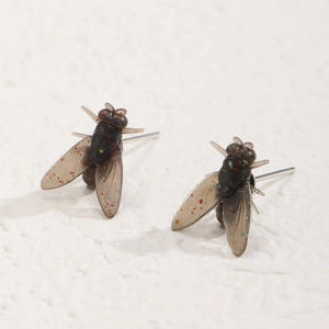 Dettaglio macro di orecchini a mosca stravaganti con paillettes e ali realistiche