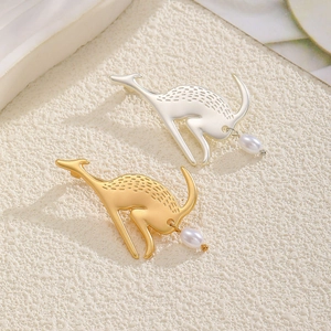 Close-up of gold and silver kangaroo earrings with pearl drops on white textured board
