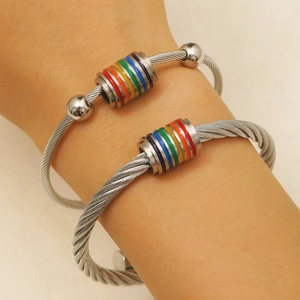 Primer plano de pulseras de cable de titanio con cilindros arcoíris en la muñeca