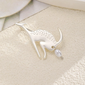Vintage matte silver deer brooch with white pearl pendant on a textured beige surface