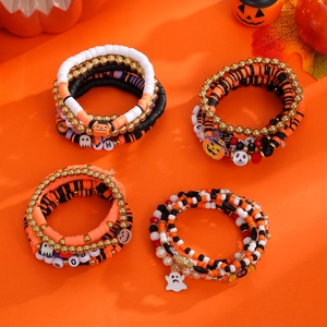 Halloween stackable beaded bracelet set with pumpkin and ghost charms on orange backdrop