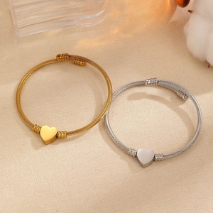 Detalle de colgantes de corazón en oro y plata en pulseras de cable trenzado