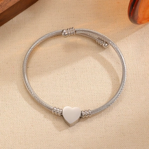 Detalle de brazalete de cable trenzado en acero con colgante de corazón y cuentas