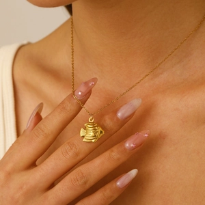 Close-up of golden tropical fish pendant on a minimalist stainless steel chain