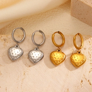 Detail of heart-shaped gold and silver earrings with textured dot patterns