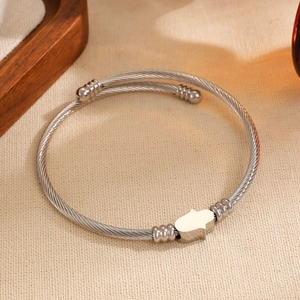 Detalle de brazalete de cable trenzado plateado con un amuleto de mano de Fátima y terminales