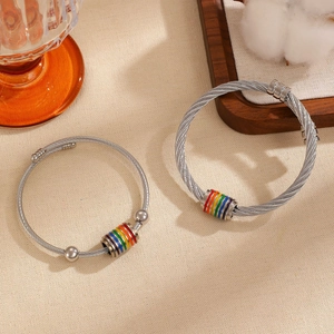 Detalle de una pulsera de cable de acero con cuentas de esmalte arcoíris y estilo industrial