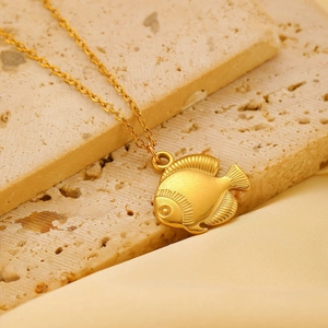 Detailed close-up of golden fish pendant with scales on elegant silk background