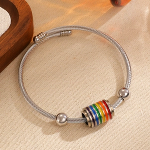 Detalle de pulsera de acero trenzado plateado con cuenta de arcoíris sobre textil blanco
