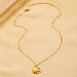 Detailed close-up of golden stainless steel fish pendant necklace on textured stone background