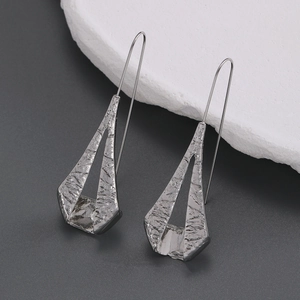Macro detail of silver geometric irregular earrings with hammered texture and long hooks