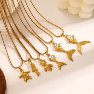 Detailed close-up of gold fish and sea turtle pendants with evil eye enamel craftsmanship