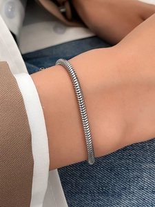 Primer plano de una pulsera de cadena de serpiente plateada con textura de escamas en la muñeca