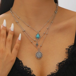 Detail of layered silver western necklace with turquoise teardrop and mandala pendant