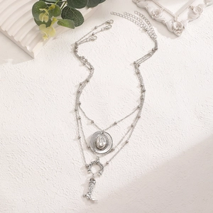 Detail of layered silver cowboy necklace with horseshoe and boot charms on soft background