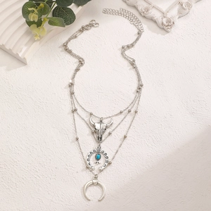 Close-up of bohemian layered silver necklace featuring bull skull and turquoise pendants