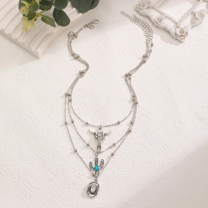 Detail view of multi-layered western cowboy necklace with bull skull and cactus pendants