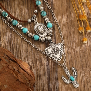 Detail of bohemian layered necklace with turquoise beads and cactus pendant on wood