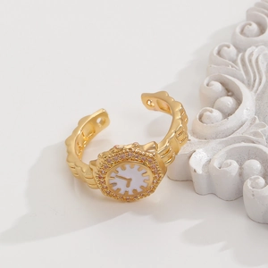 Dettaglio dell'anello a quadrante d'orologio dorato con cristalli rosa e fascia a onde