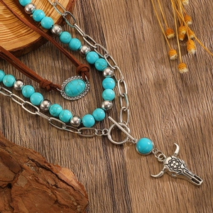Detail of layered western cowboy necklace with turquoise beads and silver bull skull pendant