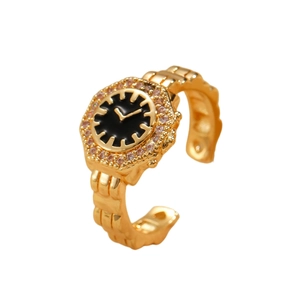 Dettaglio dell'anello dorato a forma di orologio con quadrante nero e zirconi cubici