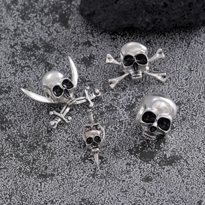 Set of four vintage silver skull pins with pirate and gothic style on grey stone surface