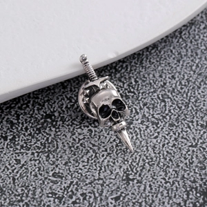 Close-up of vintage punk skull and sword brooch with aged silver finish and black enamel details