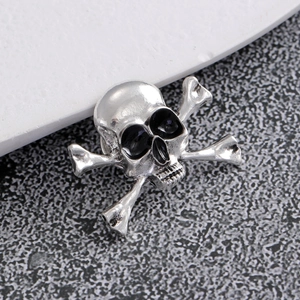 Macro shot of vintage silver skull and crossbones brooch with black enamel gothic details