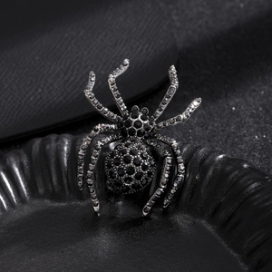 Macro shot of a black spider brooch featuring detailed gemstone inlay on dark ceramic