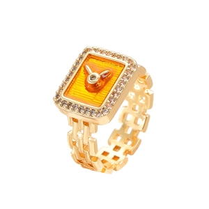 Dettaglio anello maglia d'orologio dorato con smalto arancione e incisione a forma di coniglio