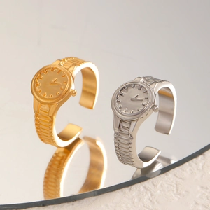 Dettaglio di anelli creativi a forma di orologio oro e argento con trame del quadrante