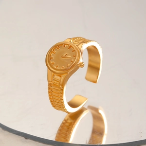 Dettaglio anello creativo a forma di orologio dorato con quadrante su superficie a specchio