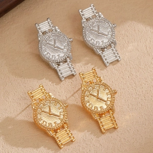 Dettaglio degli orecchini a forma di orologio oro e argento con numeri romani e opachi